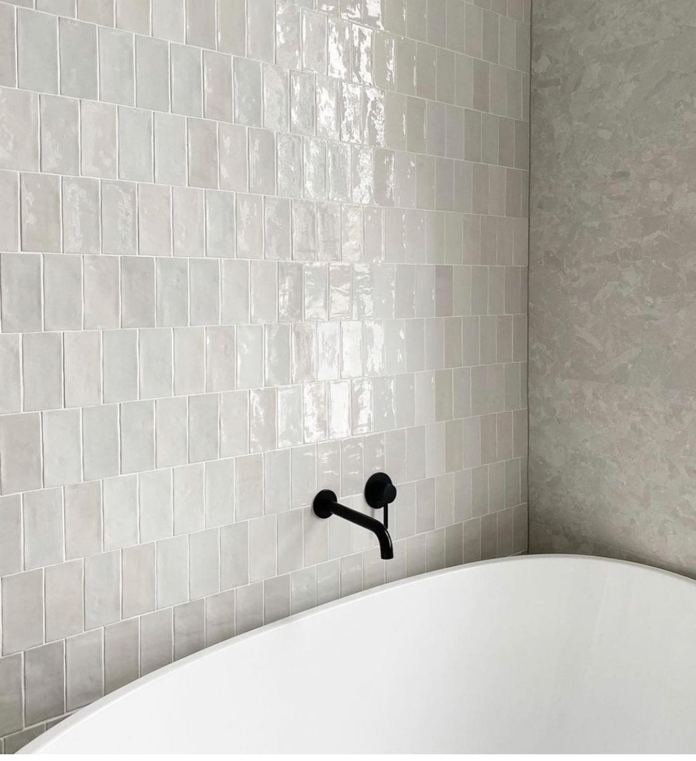 The subtle undulating surface of the tiles brings the smoothness of the bath into focus.